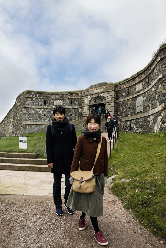 남성과 여성이 석조 요새 입구 근처에 서 있습니다. 다른 사람들이 구조물을 향해 길을 걷고 있습니다.