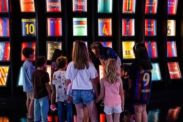 아이들은 조명이 희미한 전시관에서 액자에 담긴 축구 유니폼을 관찰합니다.