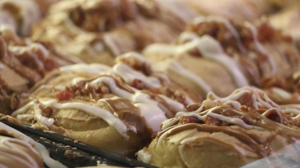 베이커리 세팅에 화이트 아이싱과 캐러멜을 얹은 시나몬 롤의 클로즈업.