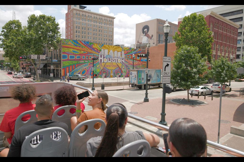 오픈탑 버스에 앉은 관광객들은 도심 거리에서 "Houston Inspired" 를 읽는 다채로운 벽화를 감상할 수 있습니다.