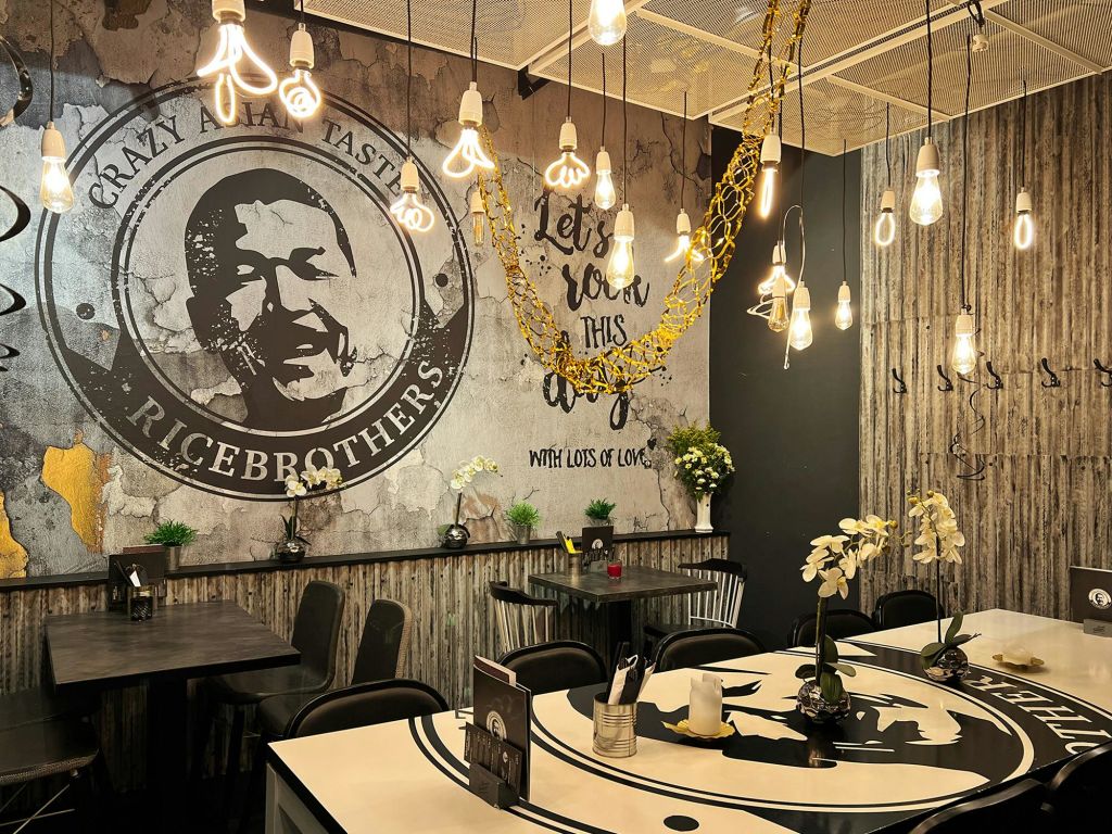 펜던트 조명, 소박한 인테리어, 벽 예술, 테이블과 선반에 꽃꽂이가 있는 레스토랑 인테리어.