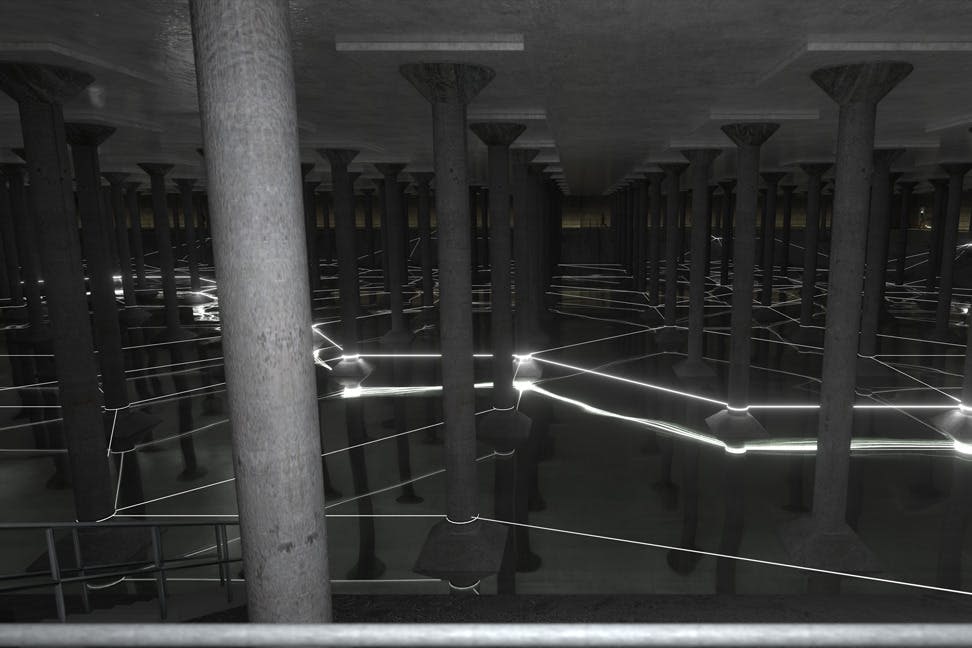 콘크리트 기둥이 줄지어 있고 빛나는 선이 물에 반사되는 지하 구조물.