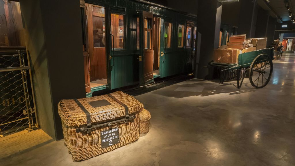 "BRUSSEL ZUID" 라벨이 붙은 고풍스러운 고리 버들 세공 짐 더미 옆에 있는 빈티지 열차입니다.