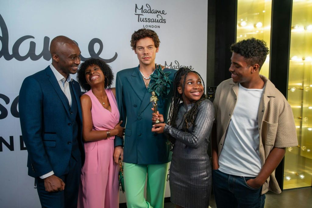 런던 마담 투소 박물관의 왁스 주위에서 네 사람이 미소를 짓고 있습니다.