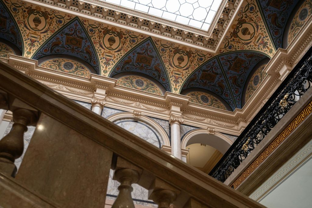 장식된 천장, 아치형 벽 틈새, 기둥, 전경에 대리석 계단 난간이 있는 화려한 인테리어.