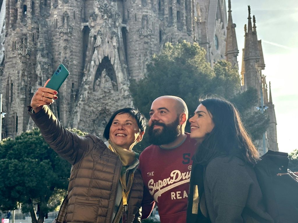 세 사람이 사그라다 파밀리아 대성당을 배경으로 셀카를 찍으며 미소를 짓고 있습니다.
