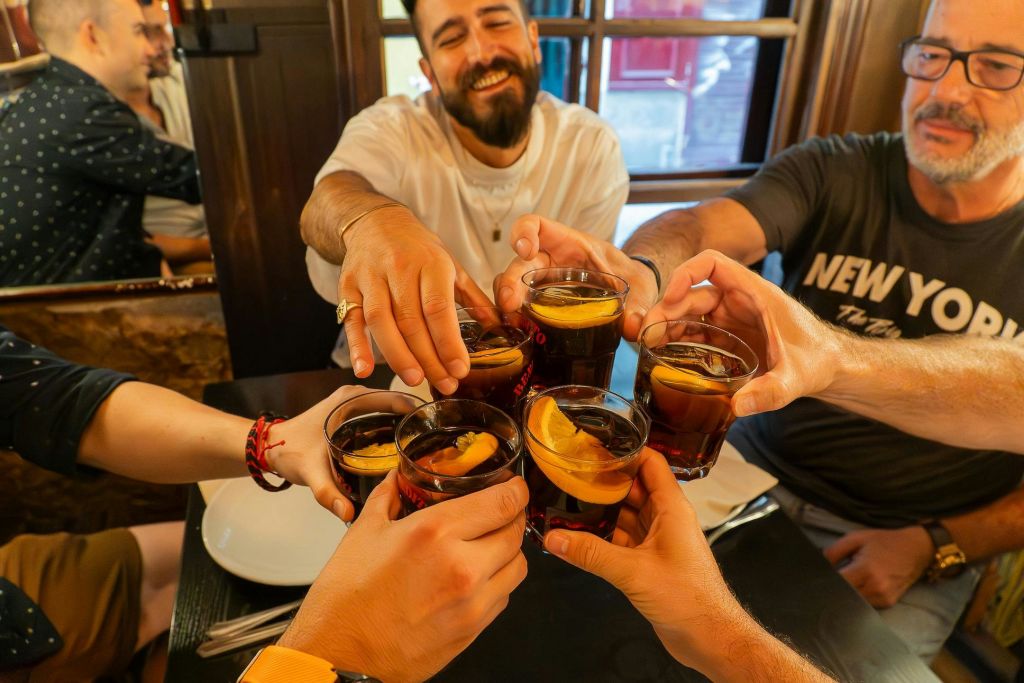 아늑한 실내 환경에서 음료를 마시며 건배하고, 미소를 짓고, 테이블에 둘러앉는 사람들이 많습니다.