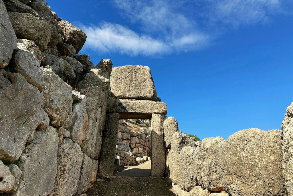 미케네의 방어벽의 일부인 푸른 하늘 아래 큰 직사각형 블록이 있는 좁은 석문.