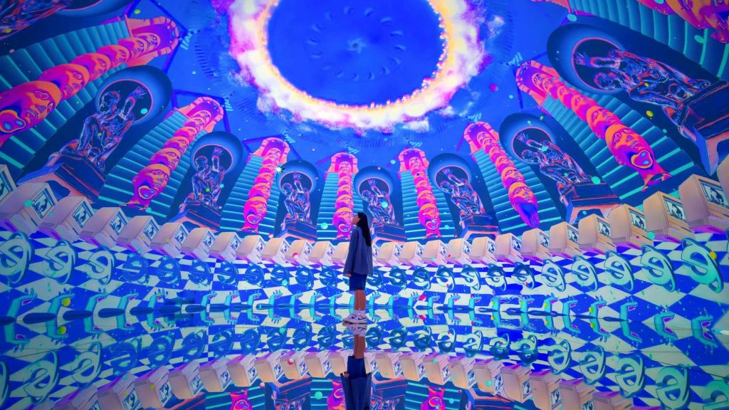 한 사람이 활기차고 대칭적인 패턴과 반사가 있는 화려하고 몰입감 넘치는 돔에 서 있습니다.