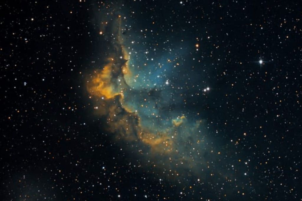 수많은 별들로 둘러싸인 파란색, 녹색 및 주황색 가스 구름이 빛나는 깊은 공간의 다채로운 성운.