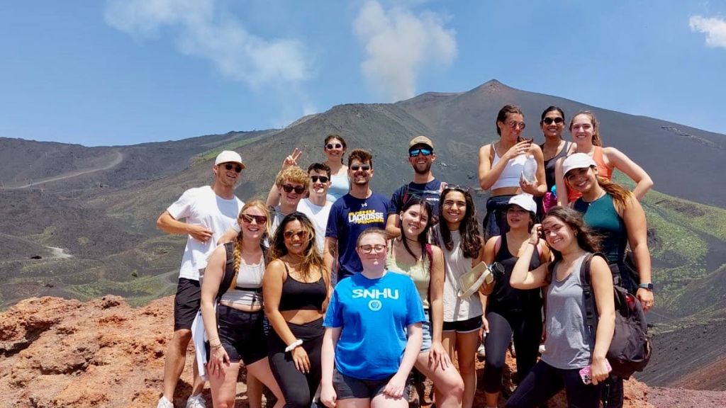 맑고 푸른 하늘 아래 흡연 화산 앞에서 포즈를 취하고 있는 16명의 일행.