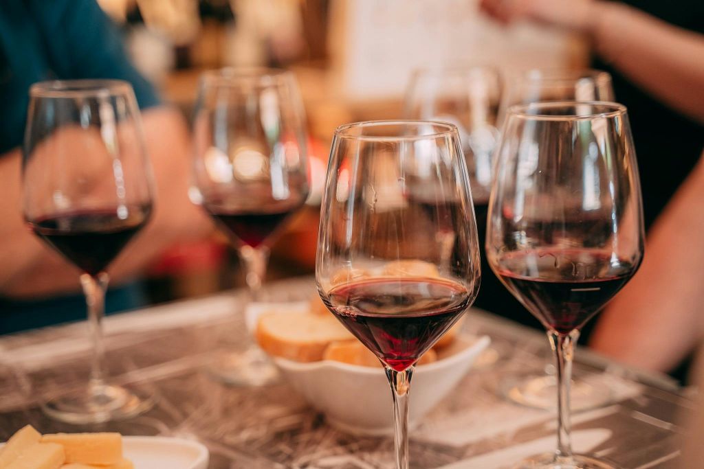 따뜻한 실내 환경에서 빵 한 그릇과 함께 테이블 위에 레드 와인 몇 잔.