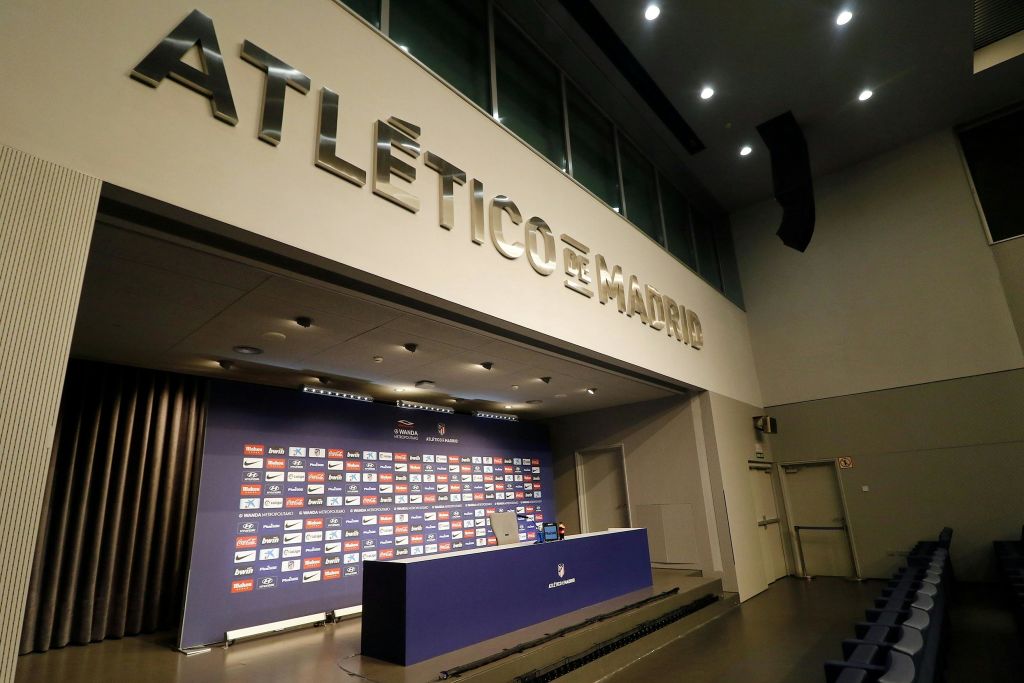 "아틀레티코 데 마드리드 (Atlético de Madrid)" 표지판, 빈 연단, 배경이 스폰서 로고로 덮인 기자회견장.