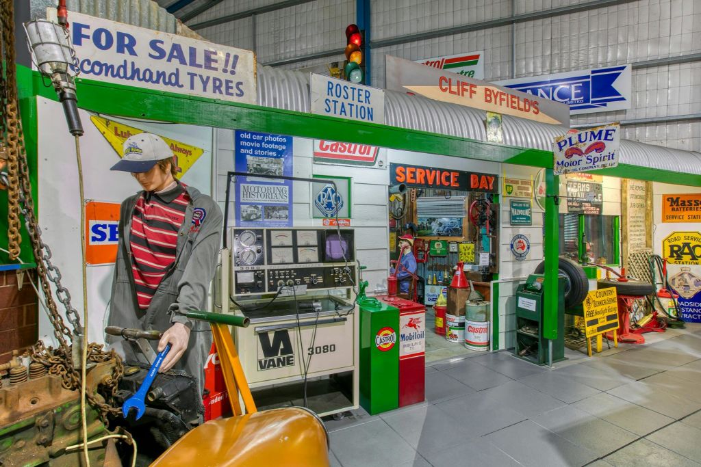 작업복, 장비, 오래된 자동차 부품, 다양한 복고풍 간판 및 광고에 참석한 빈티지 서비스 스테이션 장면.