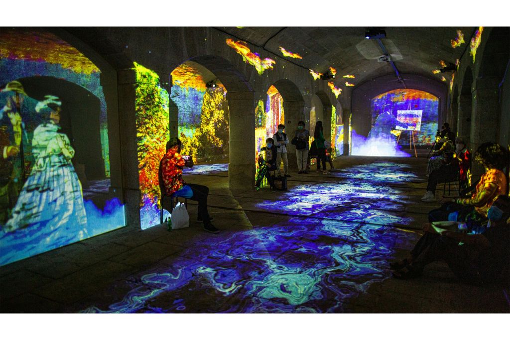 벽과 바닥에 화려한 디지털 투영이 있는 아치형 방 안의 사람들은 활기차고 몰입할 수 있는 환경을 조성합니다.