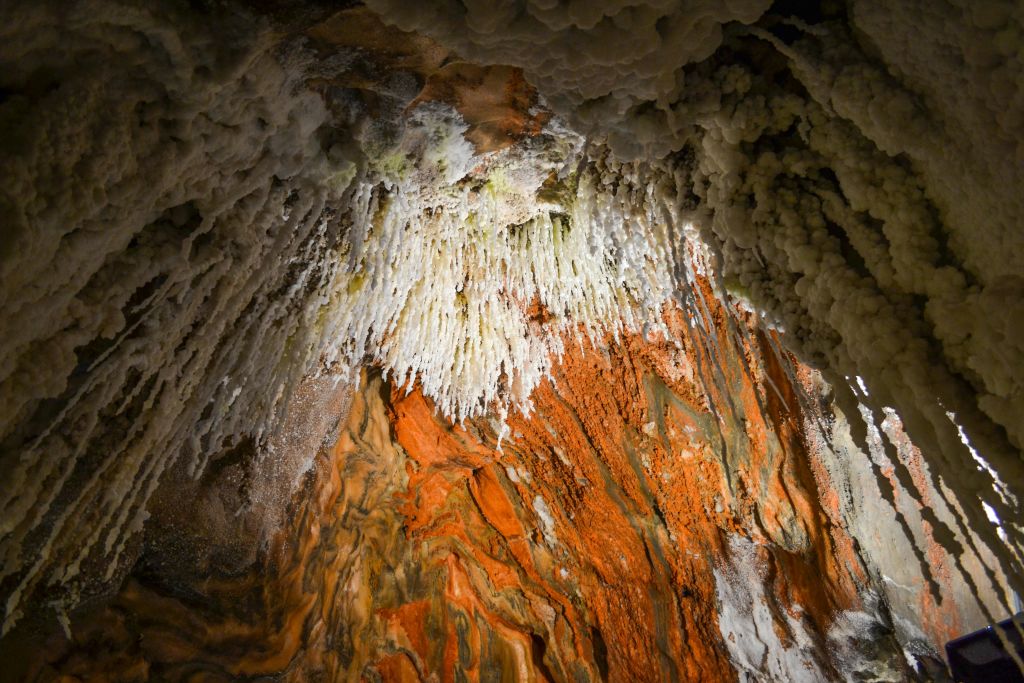 정교한 흰색 종유석과 활기찬 오렌지색과 갈색 미네랄이 형성된 동굴 천장.