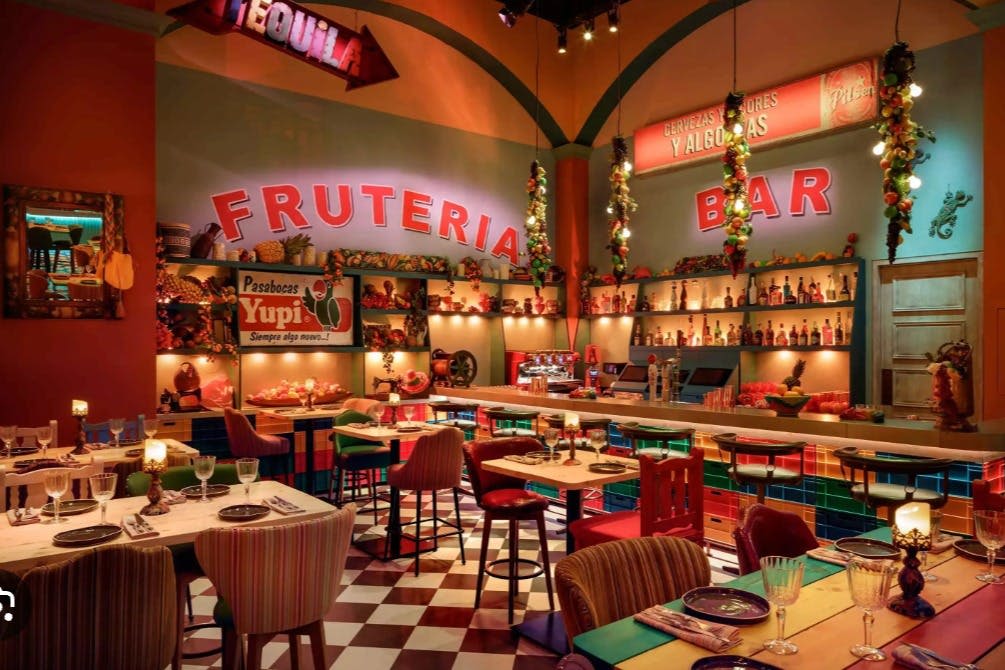 화려한 실내 바 및 레스토랑, 생동감 넘치는 인테리어, 병이 늘어선 카운터, 식사를 위한 테이블 세트, 축제 조명.