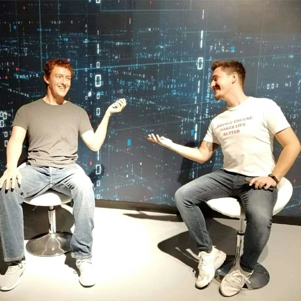 하얀 의자에 앉은 두 남자가 미소를 지으며 손을 내밀고 있습니다. 배경은 디지털 데이터 테마 벽을 묘사합니다.