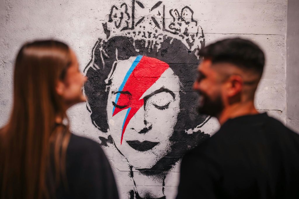 부부가 흐릿하게 바라보는 뱅크시의 벽화.