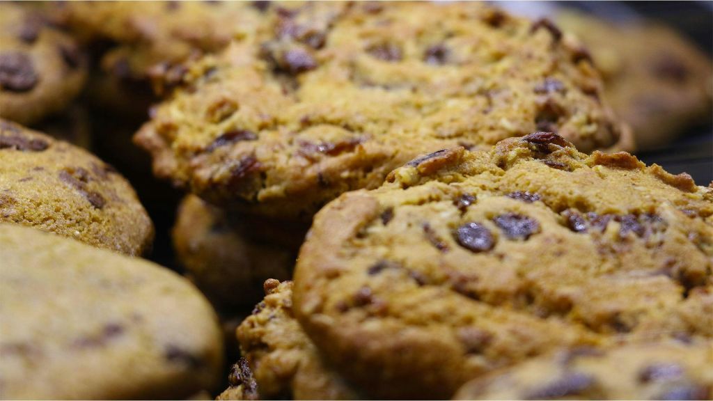 황금빛 갈색과 눈에 띄는 초콜릿 덩어리가 있는 갓 구운 초콜릿 칩 쿠키를 클로즈업합니다.