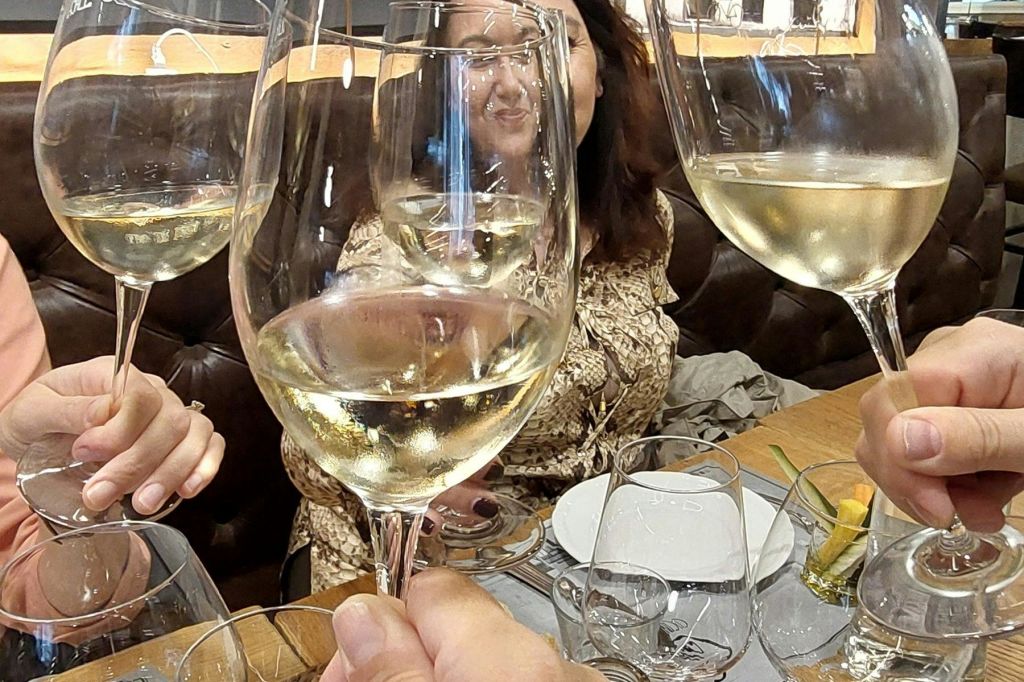 접시와 식기가 놓인 식탁에서 와인잔을 움켜쥐고, 한 사람이 웃고 있습니다.