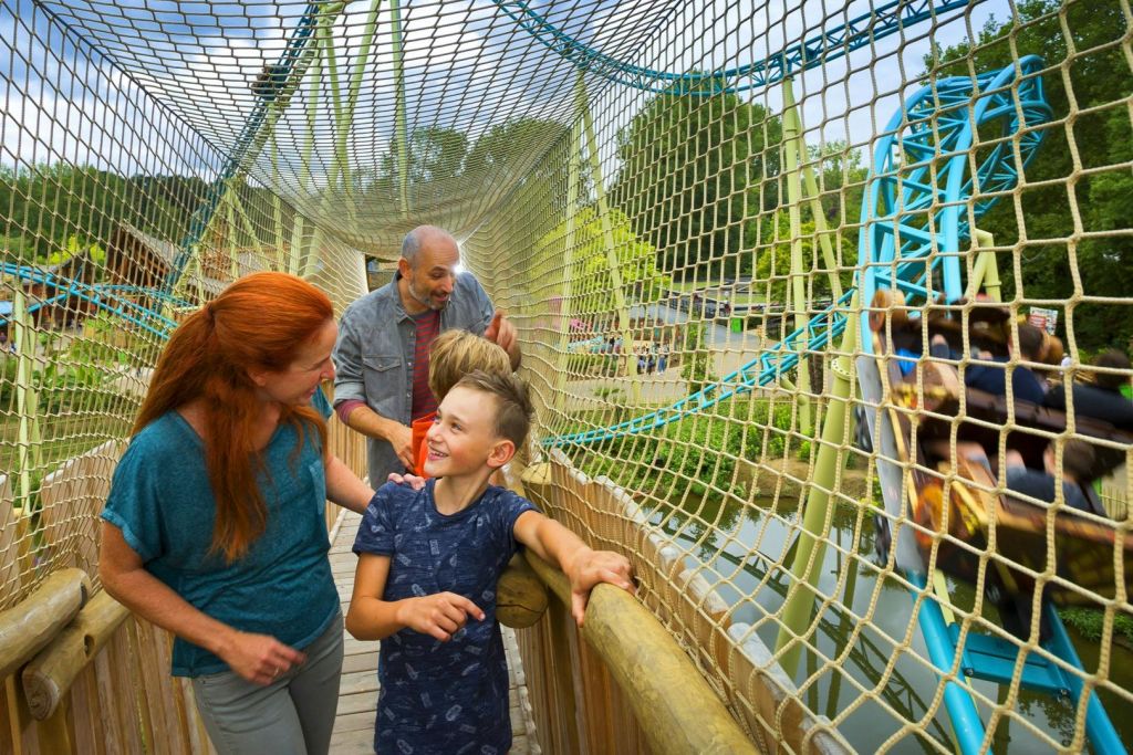 야외 공원의 밧줄 다리를 걷고 함께 웃으며 즐거운 시간을 보내는 가족.
