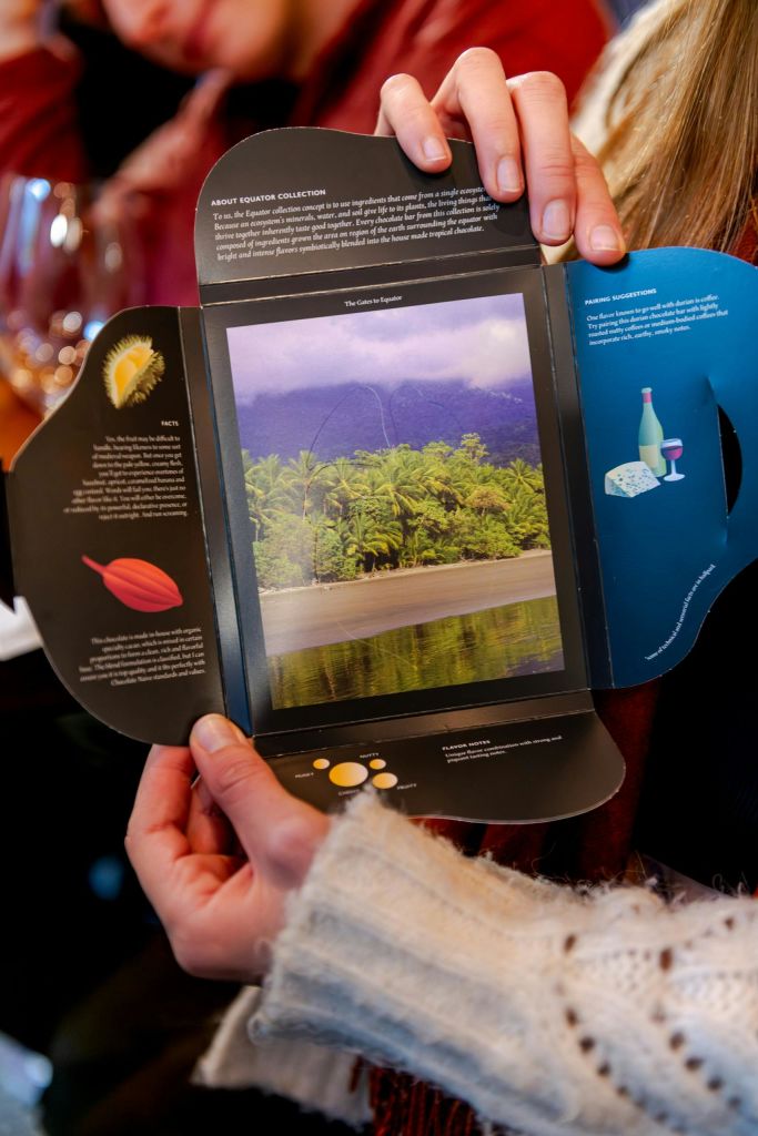 산을 배경으로 열대 숲을 형상화한 열린 소책자를 들고 있는 손.