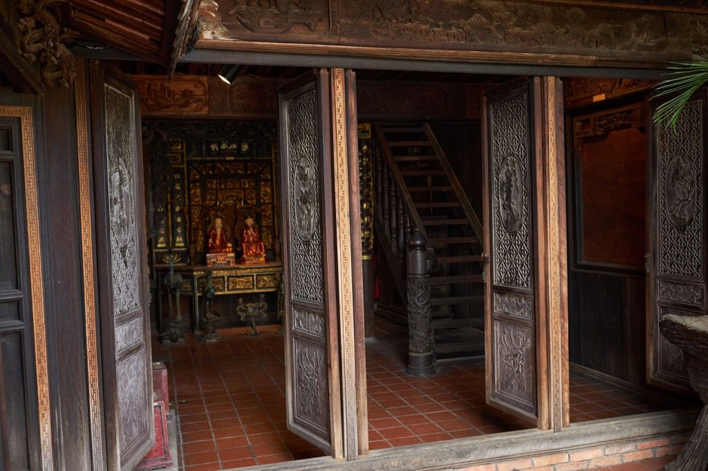 화려한 문, 타일 바닥, 계단, 장식 제단이 있는 전통적인 목조 건물의 내부 모습.