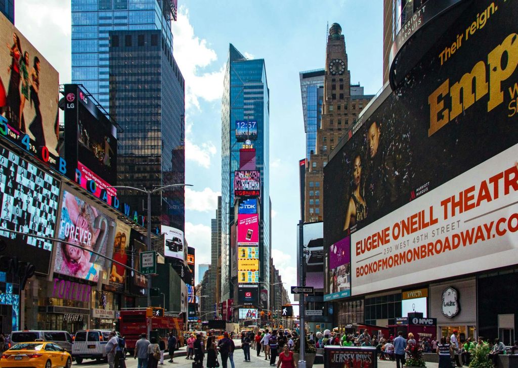 대형 디지털 광고판, 높은 건물, 걷는 사람들로 가득한 뉴욕의 타임스퀘어 전경.