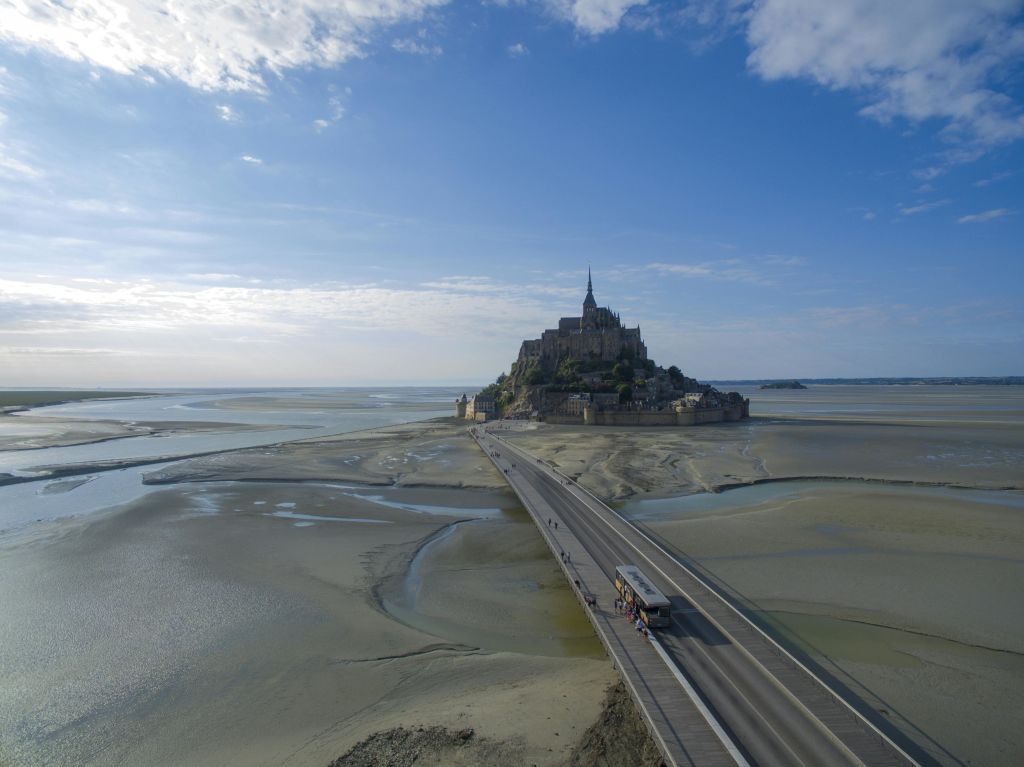 돌길은 구름이 흩날리는 푸른 하늘 아래 조수 모래사장으로 둘러싸인 역사적인 섬 대수도원으로 이어집니다.