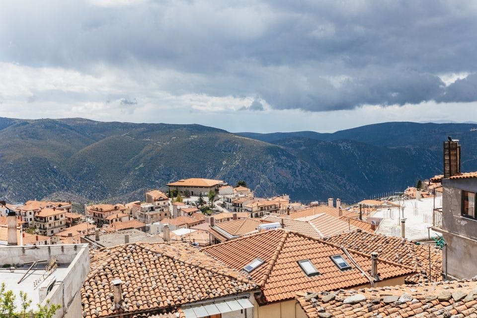 탁 트인 하늘 아래 구불구불한 산을 배경으로 테라코타 지붕이 있는 마을의 파노라마 전망을 감상할 수 있습니다.
