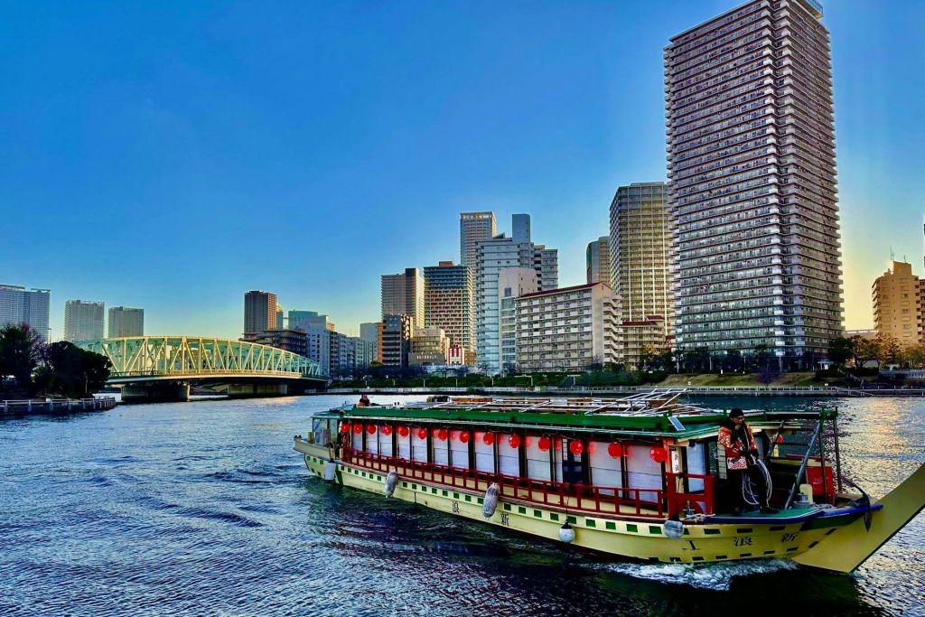 도시 고층 빌딩을 배경으로 강에 붉은 등불이 떠 있는 강 보트와 맑고 푸른 하늘 아래 다리가 있습니다.