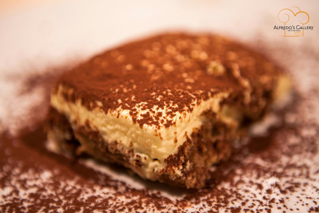 접시에 코코아 가루를 뿌린 티라미수 조각을 클로즈업했습니다.