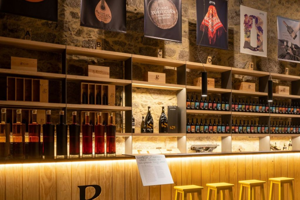 병 선반, 나무 바 카운터, 노란색 스툴, 벽에 장식 포스터가 있는 와인 숍 인테리어.