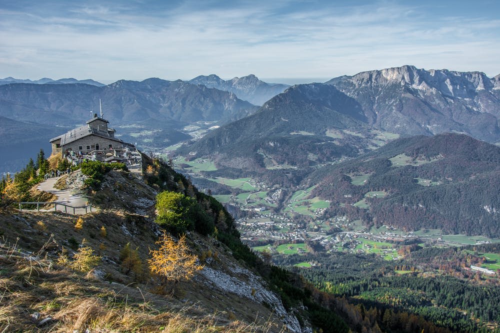 푸른 들판과 숲, 먼 산이 어우러진 계곡이 내려다보이는 언덕에 건물을 세운 산 풍경.