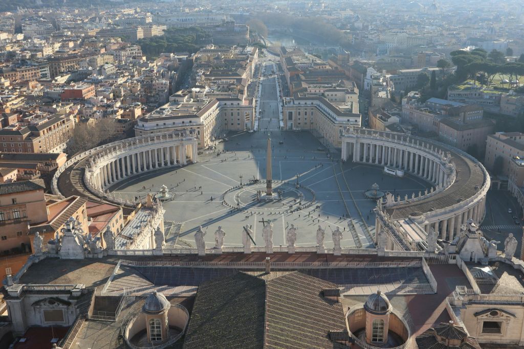 중앙의 오벨리스크가 있고, 곡선으로 둘러싸인 콜로네이드와 도시 풍경을 배경으로 한 커다란 광장의 공중 전망.