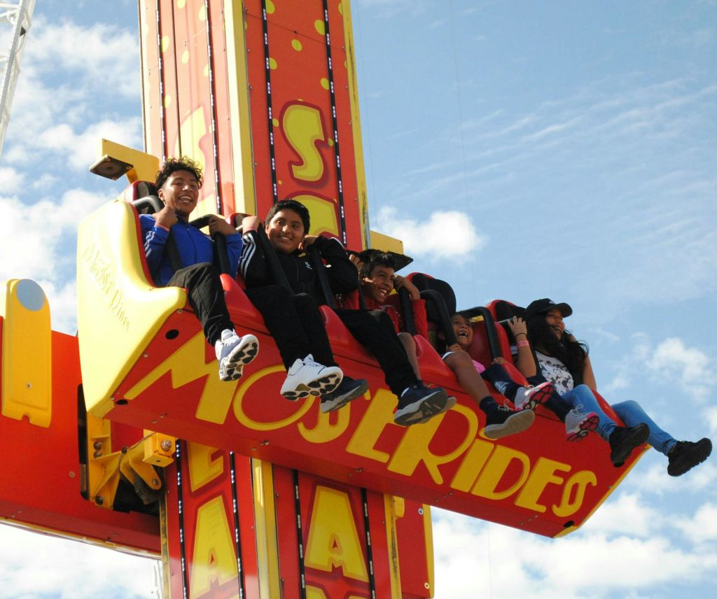 노란색과 빨간색 놀이 기구 탑에 앉아 구름이 낀 푸른 하늘을 배경으로 웃고 있습니다.