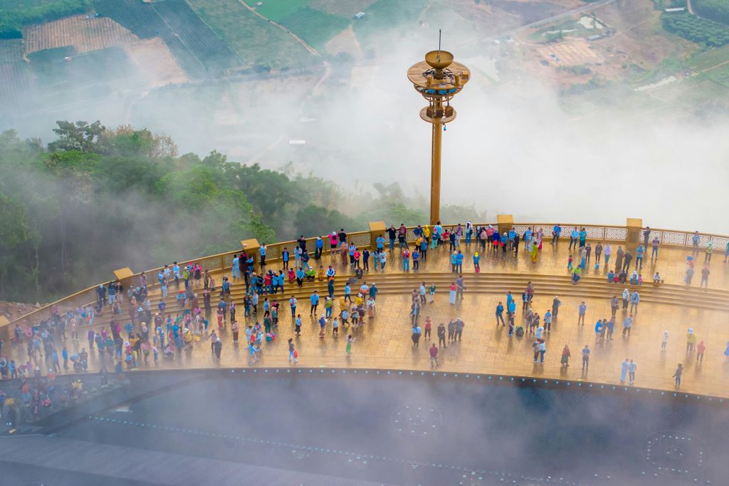 울창한 초록의 풍경이 내려다보이는 짙은 안개가 깔린 크고 높은 나무 플랫폼에 군중이 모여듭니다.