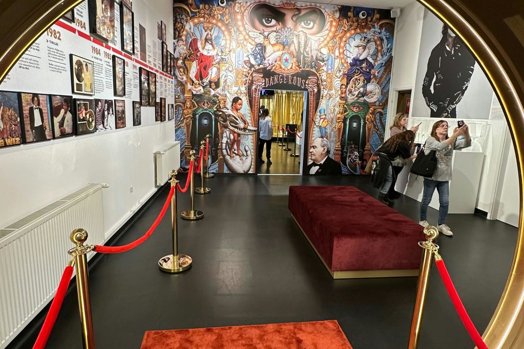 빨간색 벤치, 빨간색 로프 장벽, 정교한 디자인과 초상화가 있는 다채로운 벽화가 있는 실내 공간입니다.