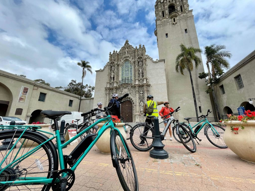 디테일한 건축물과 높은 종탑이 있는 유서 깊은 건물 앞에 여러 대의 자전거가 주차되어 있습니다.