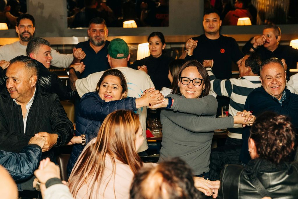 한 그룹의 사람들이 원을 그리며 손을 잡고 미소를 짓고 대화형 활동에 참여합니다.