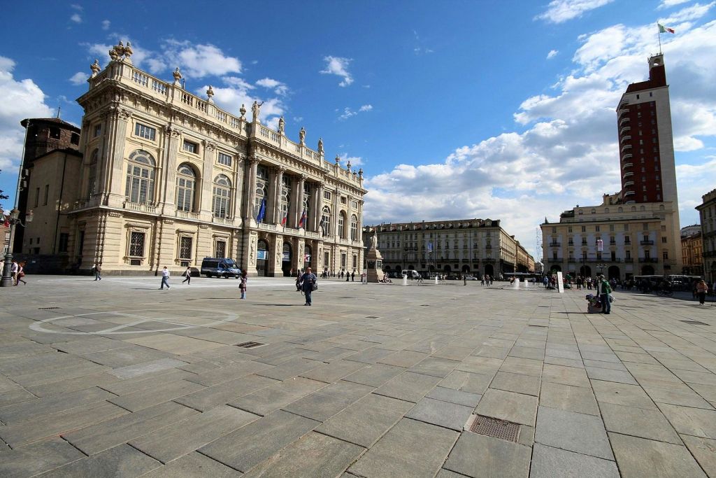 부분적으로 흐린 푸른 하늘 아래 화려한 역사적인 건물로 둘러싸인 사람들이 걷는 대형 광장.