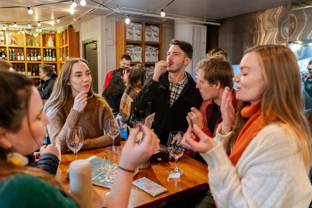 아늑한 실내 환경에서 와인잔이 놓인 나무 테이블을 둘러보며 대화를 나누는 사람들의 모임.