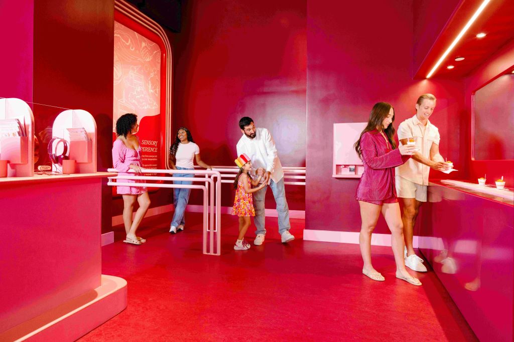 디스펜서에서 액체를 붓고 카운터 근처에 서는 등 다양한 활동을 하는 활기찬 분홍색 방에 있는 사람들.