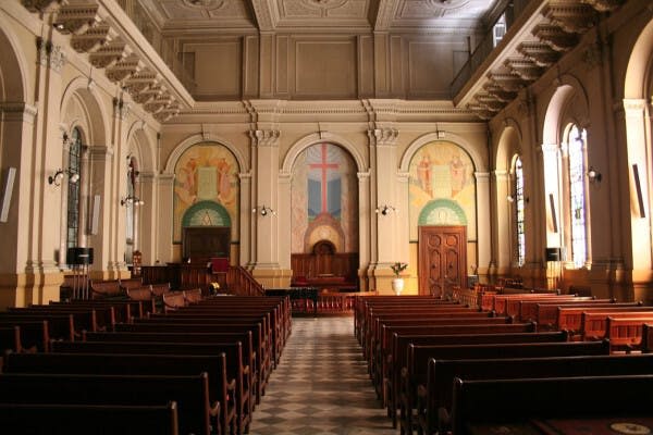 전면에 십자가와 종교적 상징을 형상화한 벽화, 높은 천장, 목조 동굴이 있는 교회 내부.