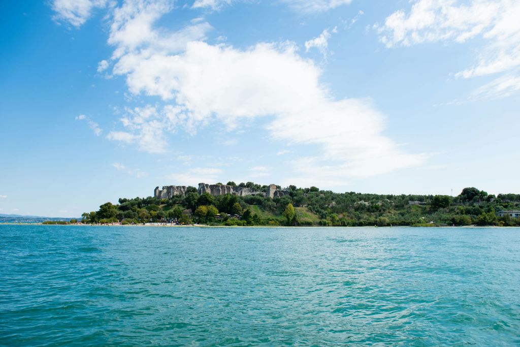 부분적으로 흐린 하늘 아래 녹음과 바위 지층으로 덮인 섬이 있는 잔잔한 물줄기.