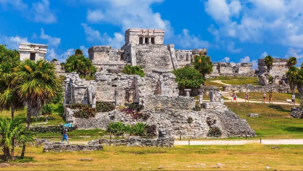 푸른 하늘 아래 눈에 띄는 계단식 구조가 특징인 녹음이 우거진 고대 석조 유적지.