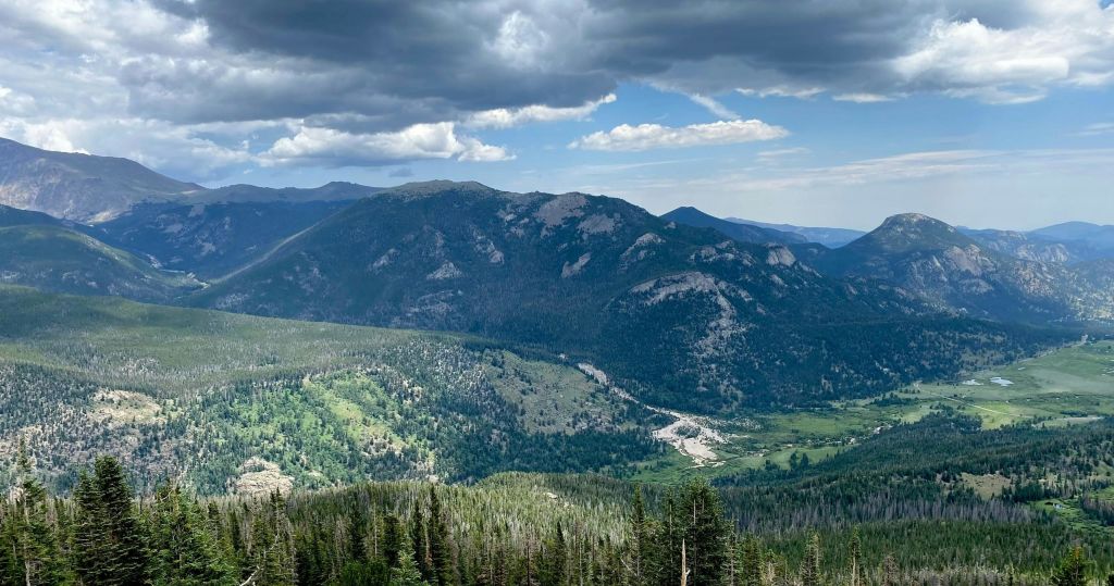 울창한 녹음, 숲이 우거진 지역, 하늘의 구름이 있는 산악 지형.