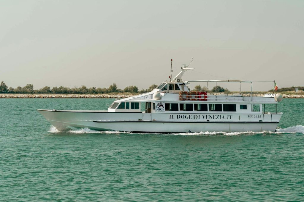 "Il Doge di Venezia" 라고 쓰여진 하얀 여객선이 맑은 하늘 아래 잔잔한 물을 가로지르고 있습니다.