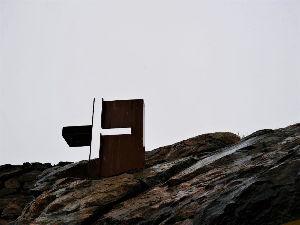 흐린 하늘 아래 바위 언덕에 금속 추상 조각.